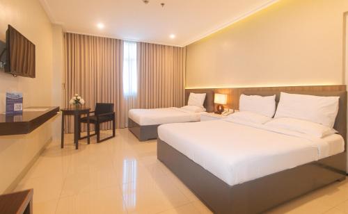 a hotel room with two beds and a desk at Iloilo Gateway Hotel and Suites by RedDoorz in Pavia
