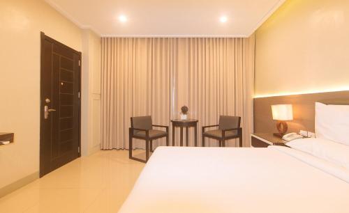 a hotel room with a bed and a table and chairs at Iloilo Gateway Hotel and Suites by RedDoorz in Pavia