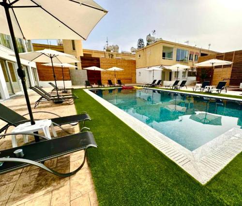Una piscina con sillas y sombrillas al lado de un edificio. en Serene Napa Suites - Heart of Ayia Napa, en Ayia Napa