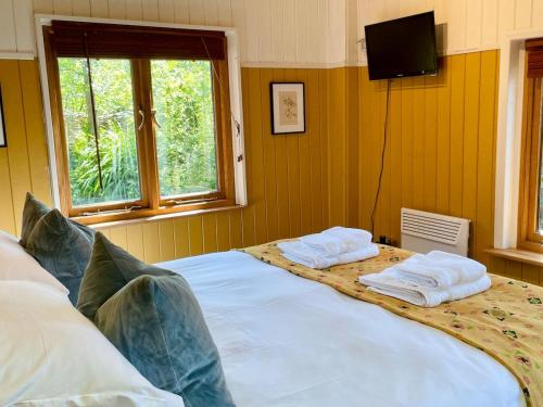 a bedroom with a large bed with towels on it at The Garden Room - Cabin on The Lizard in Cury