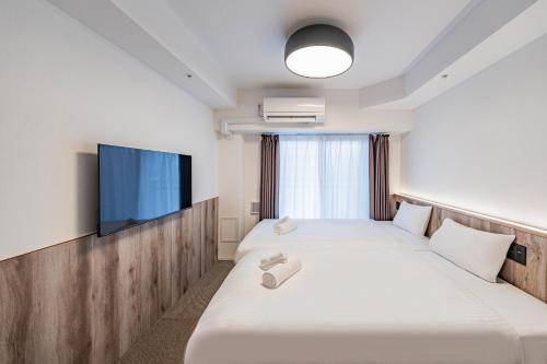 a hotel room with two beds and a flat screen tv at Apartment Hotel 11 Nagoya Sakae in Nagoya