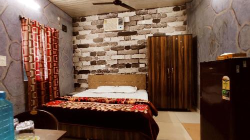 帕格瓦拉SYL HOTELS One - Comfortable and Secure Stays的一间带床和砖墙的卧室