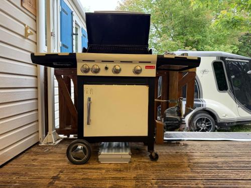 - un barbecue installé sur une terrasse couverte à côté d'une maison dans l'établissement Coin de Paradis à Hourtin, à Hourtin