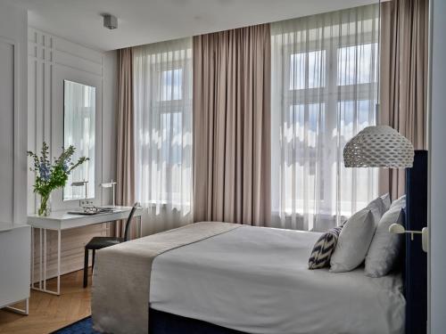 a bedroom with a bed and a desk and windows at Hotel Indigo Warsaw Nowy Świat by IHG in Warsaw