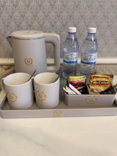 a tray with two cups and two bottles of water at Hotel Madonna SPA in Kaskelen