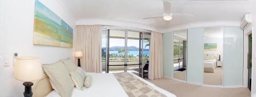 a bedroom with a bed and a view of the ocean at Poinciana 112 in Hamilton Island