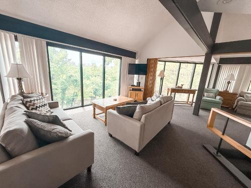 a living room with two couches and a table at Treetop Village-3bed3bapoolslakefrontlakeview in Four Seasons