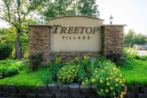 a sign for a tree top village with flowers at Treetop Village-3bed3bapoolslakefrontlakeview in Four Seasons