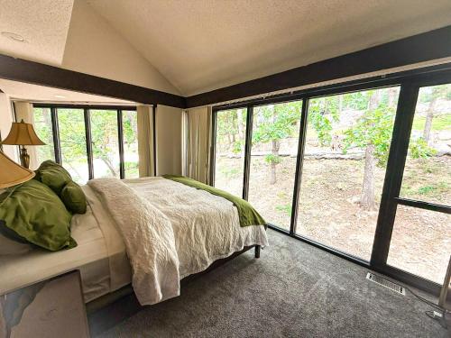 a bedroom with a bed and large windows at Treehouse Treetop Village66-3bed3bapools-8pp in Four Seasons