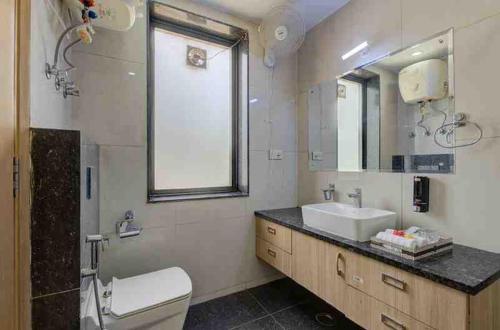 Un baño con lavabo, inodoro y espejo. en Hotel Blue Neck Hudda City Centre Fortis Hospital, en Gurgaon