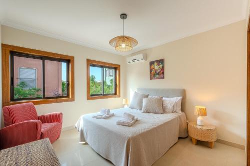 a bedroom with a bed and a chair and windows at Entre o Vale e o Mar - Vale Parra in Guia