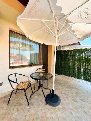 a table and two chairs under a white umbrella at Family Hotel Helios in Sunny Beach