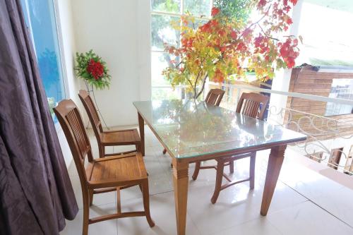 a dining room table with chairs and a glass top at Nusantara Bunga By Reccoma in Tengahgirang