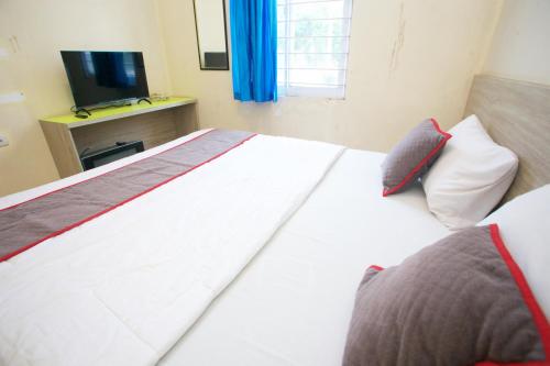 a large white bed in a room with a television at Nusantara Bunga By Reccoma in Tengahgirang