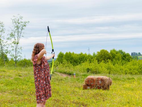 a young girl holding a bow and arrow in a field at Poilsio Arka in Nemaitonys