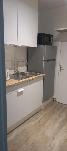 a kitchen with white cabinets and a sink and a refrigerator at Maison au calme avec jardin et grande terrasse in Brest