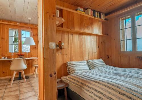 a bedroom with wooden walls and a bed and a desk at Mountainview Fireplace & Garden Bbq in Axalp