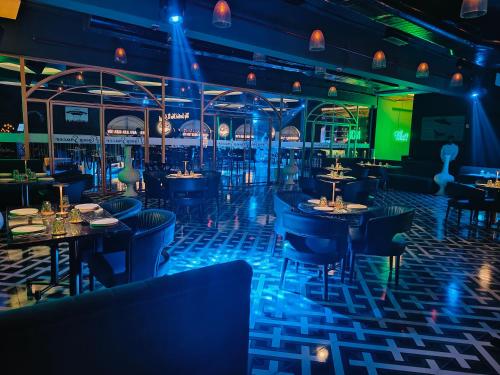 a restaurant with blue lighting and tables and chairs at Hotel Rishabh in Jhānsi