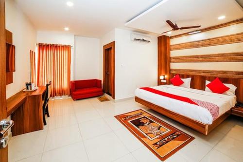 a hotel room with a bed and a red chair at Hotel Rishabh in Jhānsi