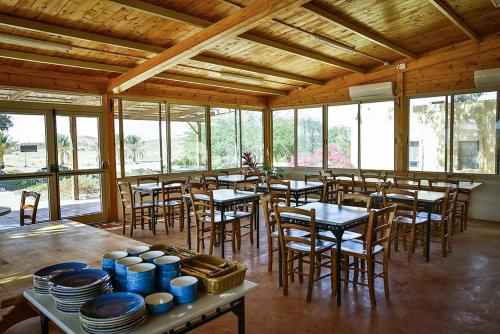 a dining room with tables and chairs and windows at Neot Semadar Eco Lodge in Naẖal Ya‘alon
