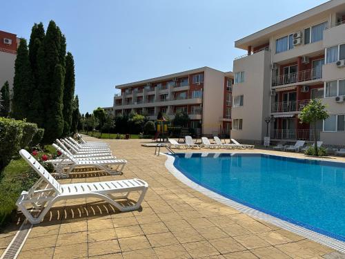 a pool with lounge chairs next to a building at The Sunny Spot in Sunny Beach