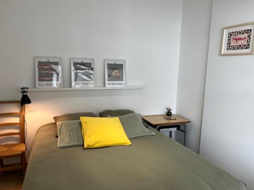 a bedroom with a bed with a yellow pillow on it at Hébergement retour de plage in Tréffiagat