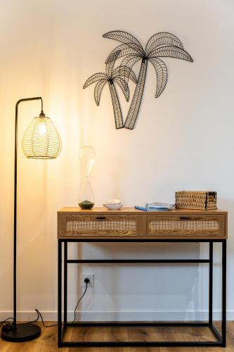 a table with a lamp and a palm tree on the wall at Chic des tropiques in Le Tampon