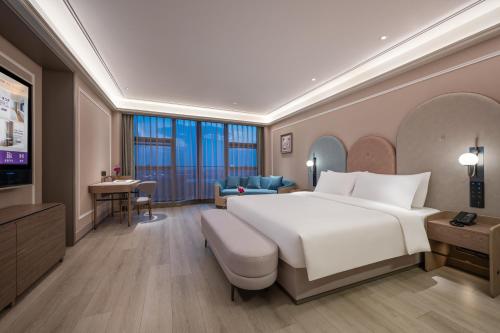 a bedroom with a large white bed and a desk at Mercure Nantong Suxitong Riverside in Nantong