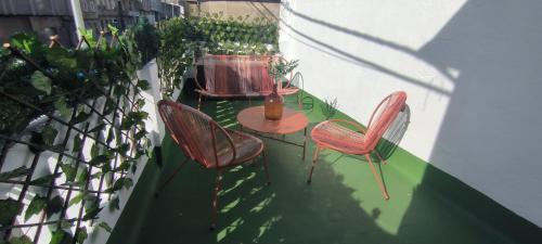 three chairs and a table on a balcony with plants at La casita in Pontevedra