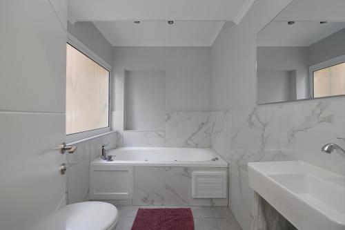 a white bathroom with a tub and a toilet and a sink at Levication Multiple Apartments - Family Stays Tiberias in Tiberias
