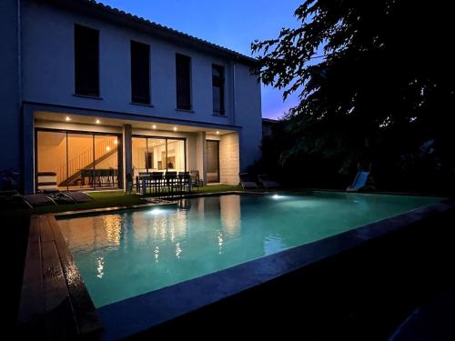 une piscine devant une maison la nuit dans l'établissement Grande maison atypique avec piscine à débordement, à Bouillargues
