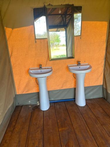 um banheiro com duas pias e um espelho em Zuhumath Tented Camps Serengeti em Parque Nacional Serengeti