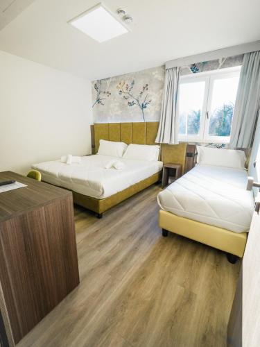 a room with two beds and a desk at Hotel Vita in Salò