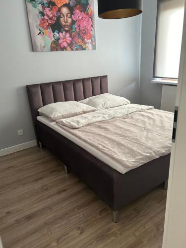 a bed in a bedroom with a painting on the wall at Apartament 5 piętro in Częstochowa