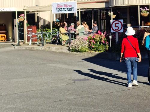 a woman walking down the street with a hat on at The Village Inn Hotel in Te Anau