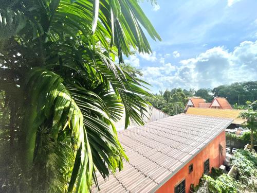 an orange building with a tile roof next to a palm tree at Krabi Rooms in Ban Khlong Chi Lat