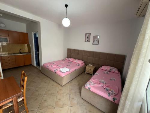 two beds in a room with a table and a kitchen at Armando Home-Free Parking Included in Vlorë