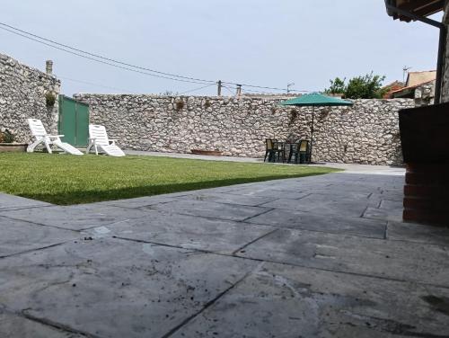 a patio with two lawn chairs and an umbrella at Casa ROSAMUNDA con gran jardín y cerca del mar in Santander