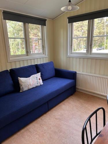a blue couch in a room with two windows at Bredsands camping och bad- Bredsandsstugor in Enköping