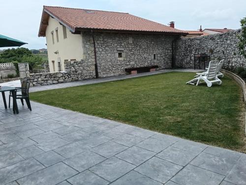 a patio with two chairs and a table in a yard at Casa ROSAMUNDA con gran jardín y cerca del mar in Santander
