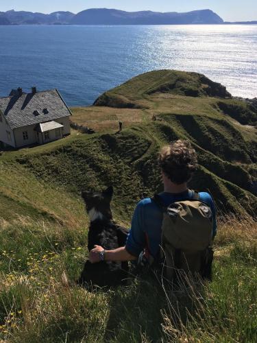 a man with a backpack and a dog sitting on a hill at Stavetunet in Stadlandet