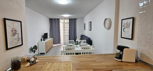 Una sala de estar blanca con una mesa y una sala de estar. en Edén Los Cristianos, en Los Cristianos