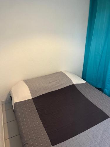 - un lit dans une chambre dotée d'un rideau bleu dans l'établissement Maison 3ch 250m mer - piscine - Clim, à Sainte-Marie-la-Mer