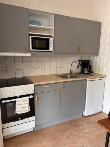 a kitchen with white cabinets and a sink and a microwave at Bredsands camping och bad- Bredsandsstugor in Enköping