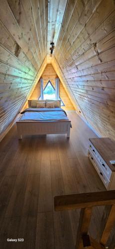 a bed in a tiny house with a wooden ceiling at Wild A-frame in Baile Felix