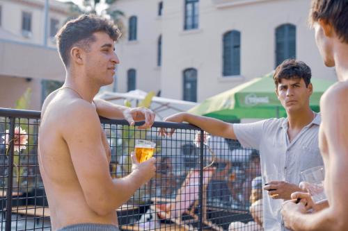 a man holding a glass of beer in a group of men at Ostello Bello Palermo in Palermo