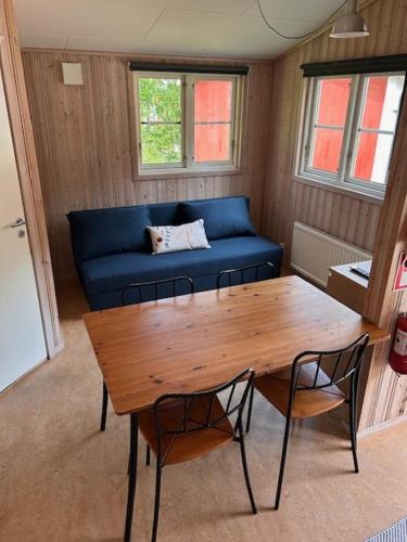 a living room with a table and a blue couch at Bredsands camping och bad- Bredsandsstugor in Enköping