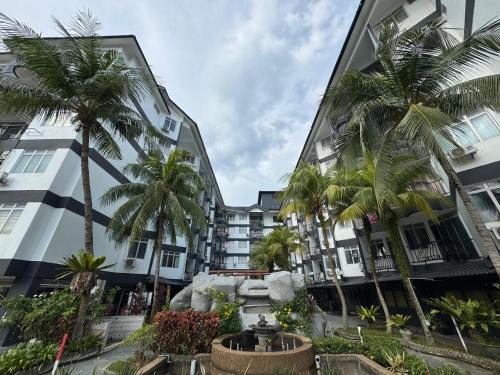 a building with palm trees in front of it at Golden Straits Villas Beach Resort - Nomad Homestay in Port Dickson