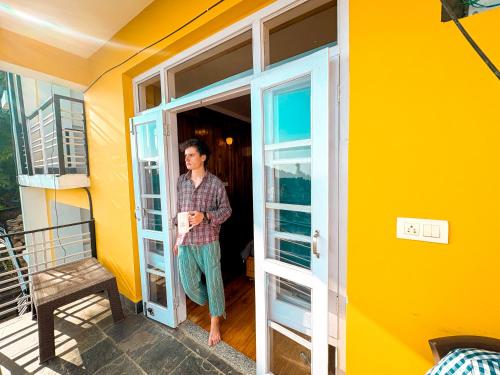 a woman standing in a doorway of a house at Young Monk Hostel & Cafe Dharamkot in McLeod Ganj