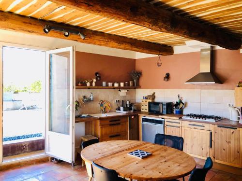 - une cuisine avec une table en bois et un plafond en bois dans l'établissement Magnifique maison sur la montagne de Lure, à Saint-Étienne-les-Orgues
